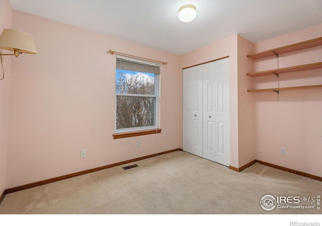 unfurnished bedroom with light colored carpet and a closet