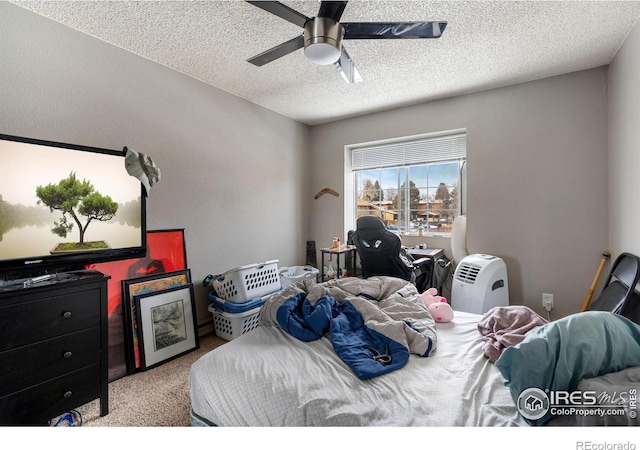 carpeted bedroom with ceiling fan and a textured ceiling