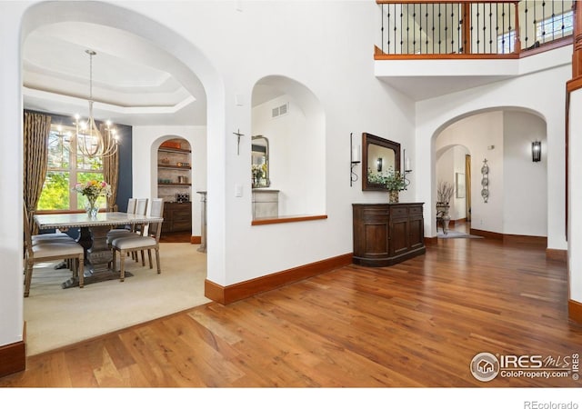 foyer entrance with a chandelier, hardwood / wood-style floors, and a raised ceiling