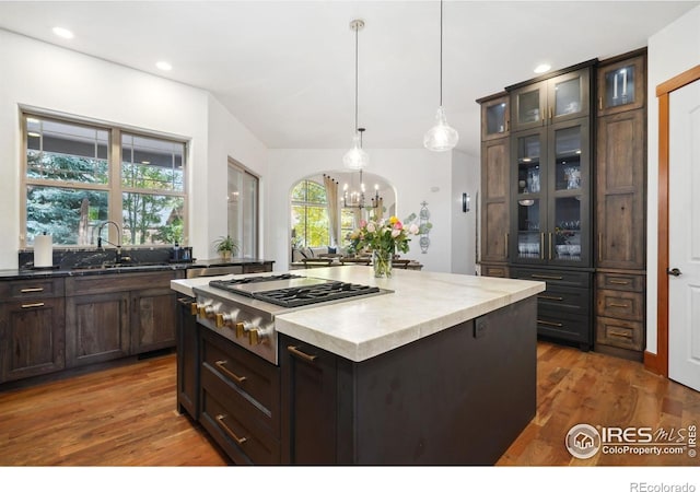 kitchen with dark brown cabinets, sink, a chandelier, a kitchen island, and hanging light fixtures