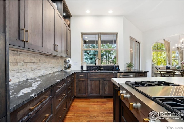 kitchen featuring sink, light hardwood / wood-style flooring, dark stone countertops, dark brown cabinetry, and stainless steel gas cooktop