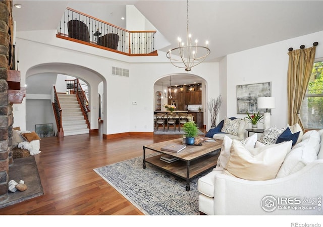 living room featuring dark wood-type flooring, a chandelier, and a high ceiling