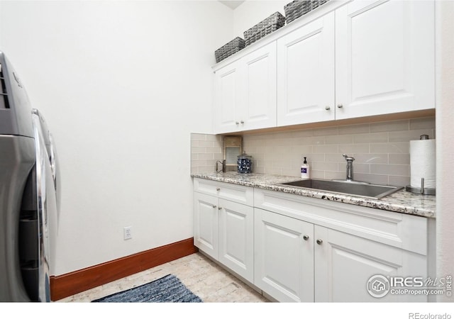 kitchen featuring washer / dryer, backsplash, white cabinetry, and sink