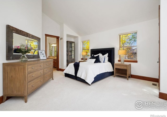 bedroom with ensuite bathroom, lofted ceiling, and light carpet