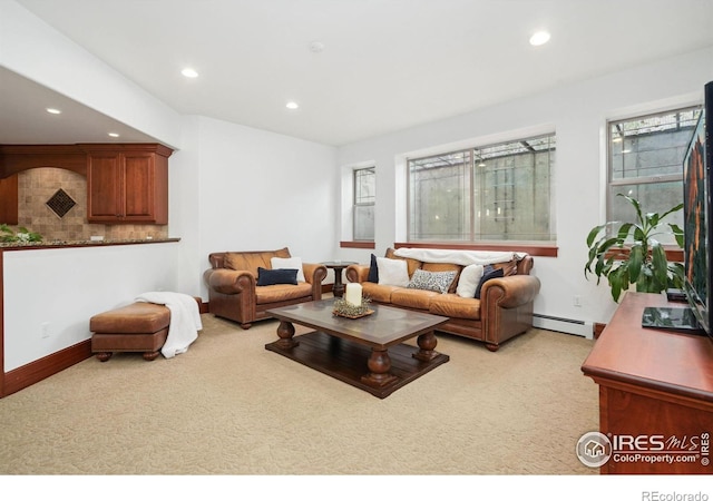 living room featuring a healthy amount of sunlight, baseboard heating, and light carpet