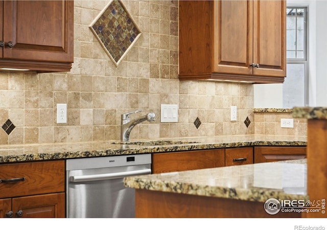 kitchen with backsplash, stainless steel dishwasher, light stone countertops, and sink