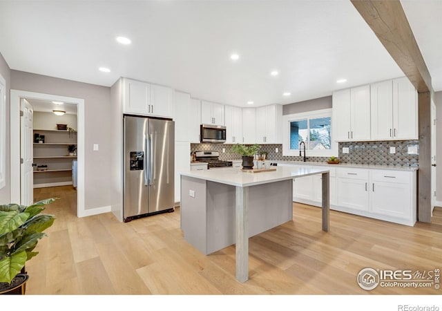 kitchen featuring appliances with stainless steel finishes, a breakfast bar, light hardwood / wood-style flooring, white cabinets, and a center island