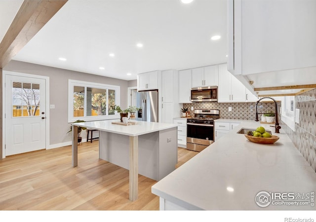 kitchen with white cabinets, a kitchen breakfast bar, a center island, and stainless steel appliances