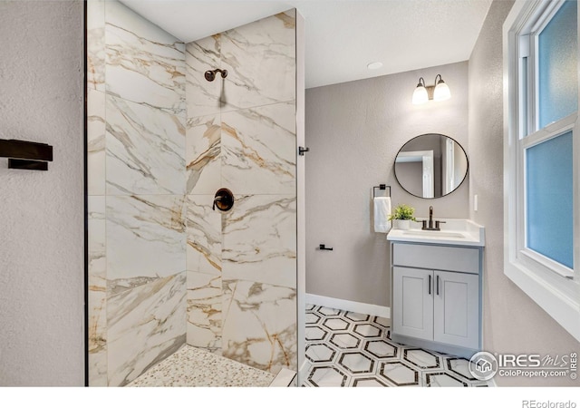 bathroom with tiled shower and vanity