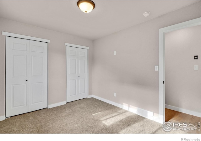 unfurnished bedroom featuring carpet flooring and multiple closets