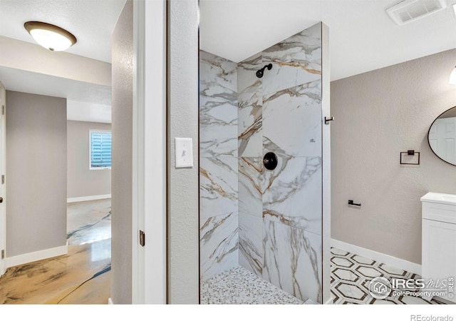 bathroom with a tile shower and vanity