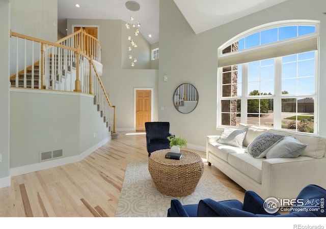 living room with light hardwood / wood-style flooring and high vaulted ceiling