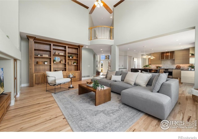 living room featuring ceiling fan, light hardwood / wood-style flooring, and a towering ceiling