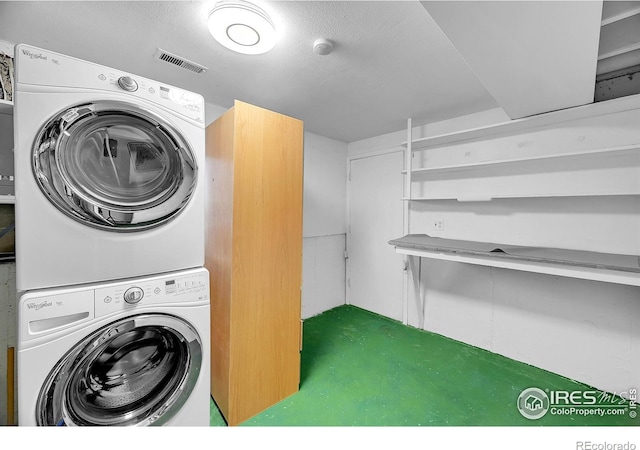 clothes washing area featuring a textured ceiling and stacked washer / dryer