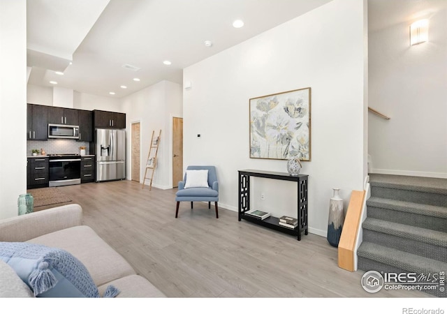 living room with a towering ceiling and light hardwood / wood-style flooring