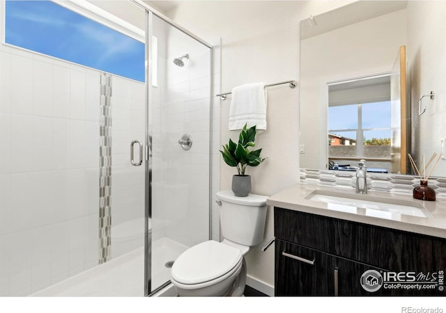 bathroom with a shower with door, vanity, and toilet