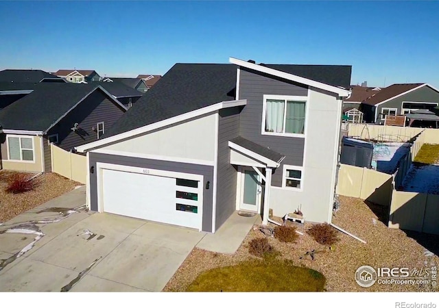 view of front facade with driveway, an attached garage, a residential view, and fence