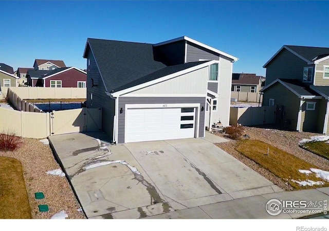 view of front of property featuring driveway, a garage, a residential view, and fence