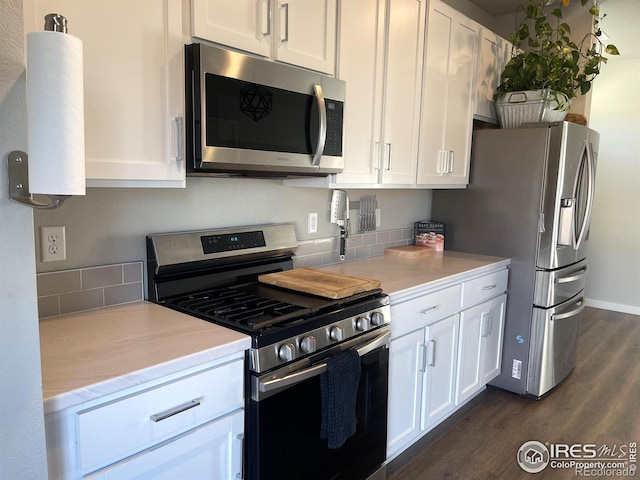 kitchen with baseboards, white cabinets, appliances with stainless steel finishes, dark wood-type flooring, and light countertops