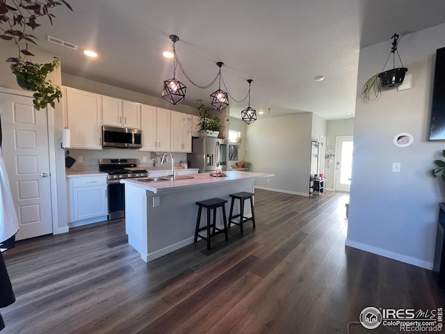 kitchen with white cabinets, a kitchen island with sink, stainless steel appliances, and light countertops