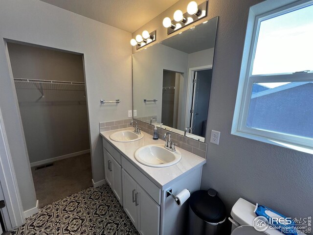 full bathroom with double vanity, visible vents, toilet, and a sink