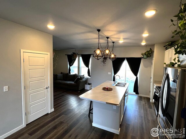 kitchen with white cabinets, an island with sink, appliances with stainless steel finishes, hanging light fixtures, and a sink