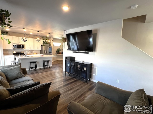 living room with dark wood-type flooring, visible vents, and baseboards