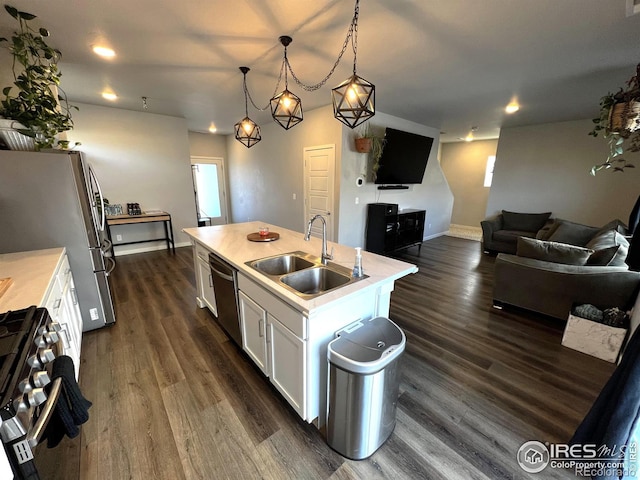 kitchen with decorative light fixtures, appliances with stainless steel finishes, a kitchen island with sink, white cabinets, and a sink