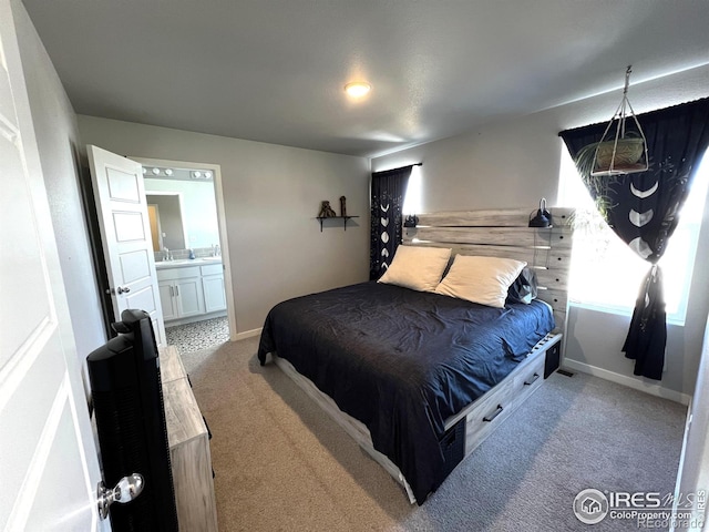 bedroom featuring light carpet, baseboards, and connected bathroom