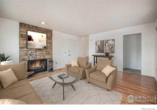 living room featuring a fireplace, wood-type flooring, and a textured ceiling