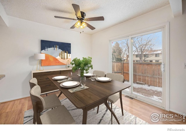 dining space featuring ceiling fan, a textured ceiling, and light wood-type flooring