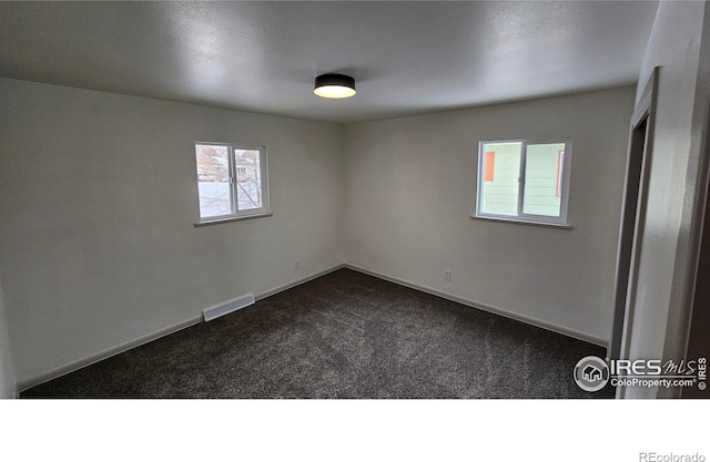 spare room featuring dark colored carpet