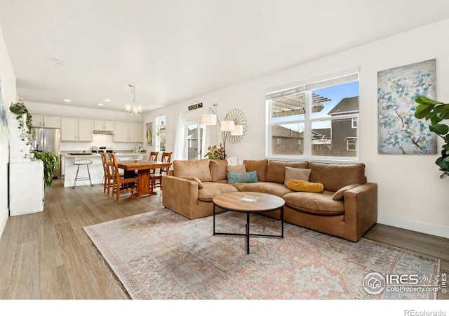 living room with an inviting chandelier and light hardwood / wood-style flooring