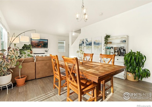 dining space with hardwood / wood-style flooring and an inviting chandelier