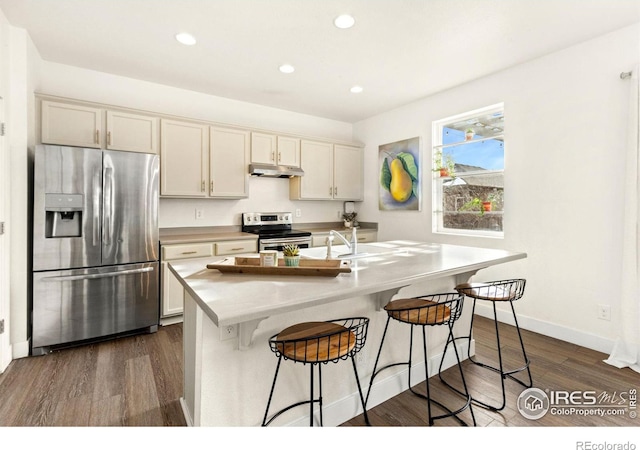 kitchen featuring appliances with stainless steel finishes, dark hardwood / wood-style flooring, a kitchen island with sink, and sink