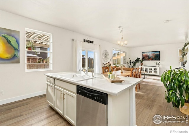 kitchen with stainless steel dishwasher, hanging light fixtures, a kitchen island with sink, white cabinets, and sink