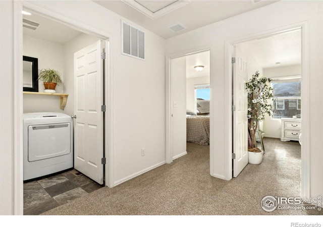 hall with washer / dryer, plenty of natural light, and dark colored carpet