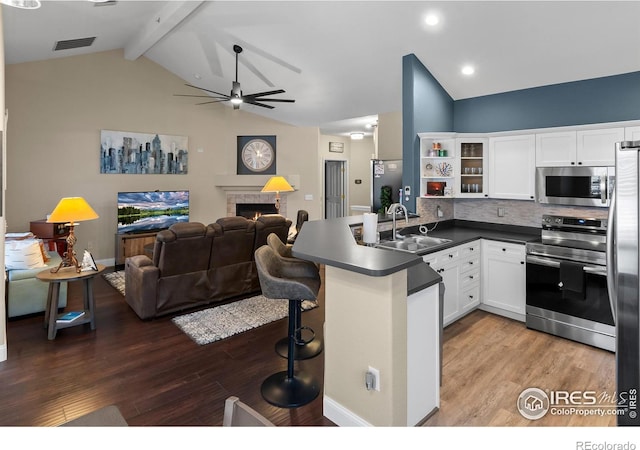 kitchen featuring appliances with stainless steel finishes, lofted ceiling with beams, sink, white cabinets, and kitchen peninsula