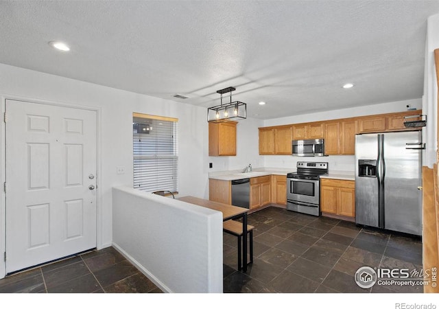 kitchen featuring decorative light fixtures, sink, a textured ceiling, and stainless steel appliances