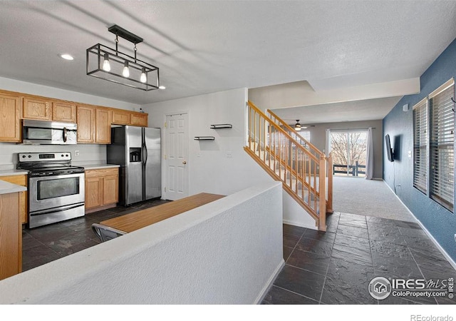 kitchen with stainless steel appliances, ceiling fan, and decorative light fixtures