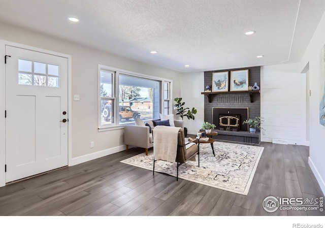 living room with a textured ceiling, a fireplace, and dark wood-type flooring