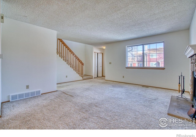 unfurnished living room featuring light carpet, a textured ceiling, and a stone fireplace