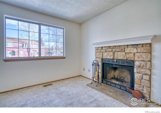 unfurnished living room featuring a textured ceiling, carpet floors, a fireplace, and a wealth of natural light