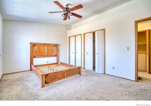 unfurnished bedroom with a textured ceiling, ceiling fan, light colored carpet, and two closets