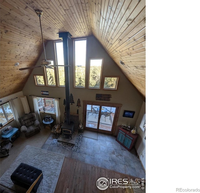 living room with a wood stove, ceiling fan, wooden ceiling, and lofted ceiling