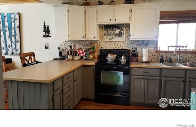 kitchen with sink, kitchen peninsula, black / electric stove, gray cabinets, and white cabinets