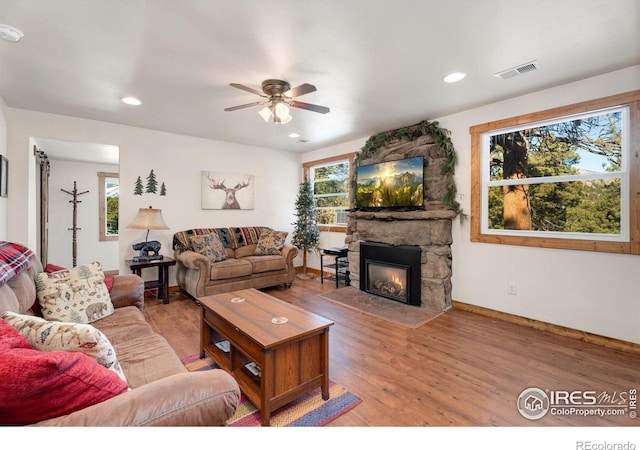 living room featuring hardwood / wood-style floors, ceiling fan, and a fireplace