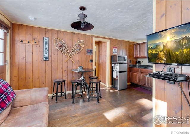 kitchen featuring a textured ceiling, crown molding, stainless steel appliances, and dark hardwood / wood-style floors