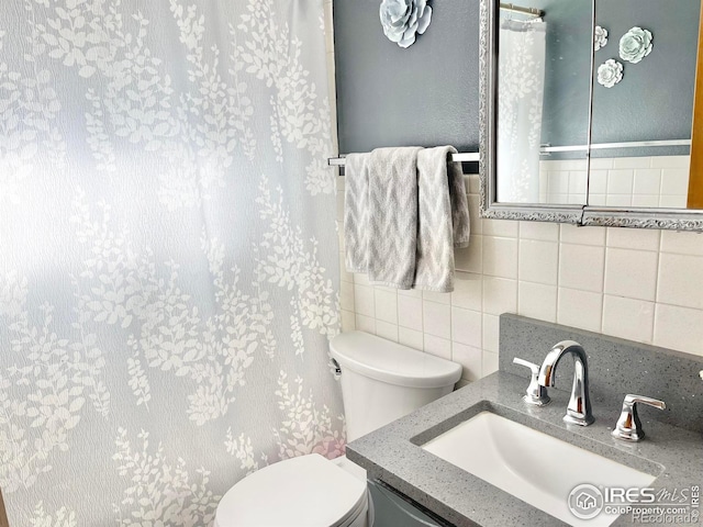 bathroom with vanity, toilet, backsplash, and tile walls