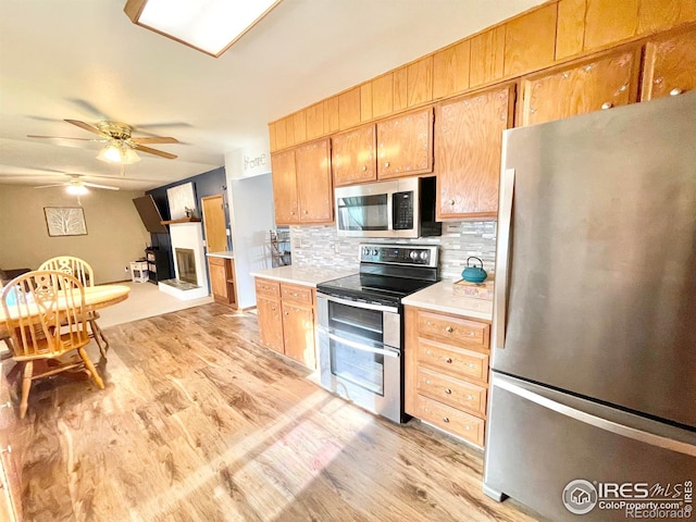 kitchen featuring decorative backsplash, ceiling fan, stainless steel appliances, and light wood-type flooring